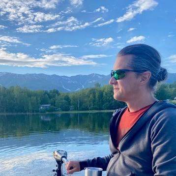 A staff member out on a calm lake with mountains in the distance.